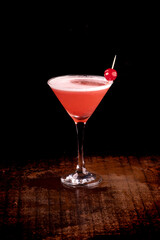 angle view strawberry martini cocktail glass with cherry and foam dark background over wooden table