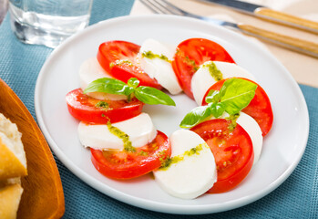 Caprese salad with fresh tomatoes, mozzarella cheese and basilic herb, dish of Italian cuisine