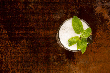 refreshing long juice with mojito foam, mint on wooden table top view