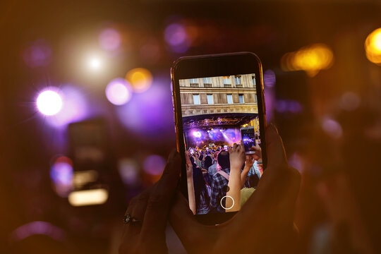 People holding their smartphones at concert and taking pictures.