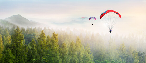 Paragliding in the sky. Paraglider  flying over Landscape sun set Concept of extreme sport, taking adventure challenge. - obrazy, fototapety, plakaty