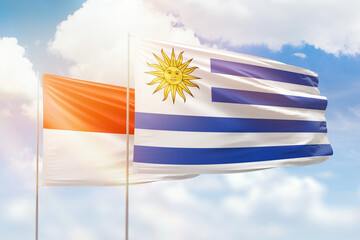 Sunny blue sky and flags of uruguay and indonesia