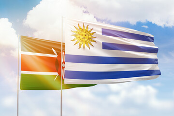 Sunny blue sky and flags of uruguay and kenya