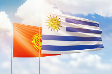 Sunny blue sky and flags of uruguay and kyrgyzstan