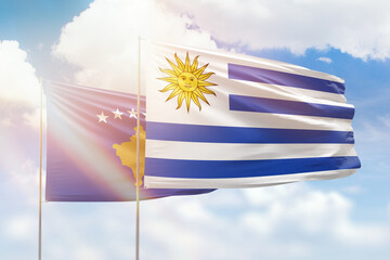 Sunny blue sky and flags of uruguay and kosovo