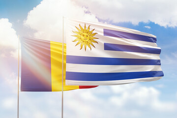 Sunny blue sky and flags of uruguay and romania