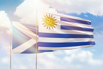 Sunny blue sky and flags of uruguay and scotland