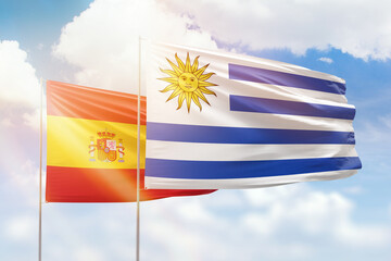 Sunny blue sky and flags of uruguay and spain