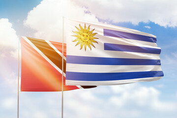 Sunny blue sky and flags of uruguay and trinidad and tobago