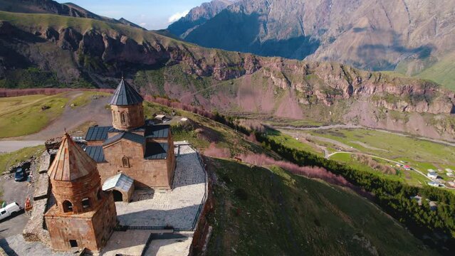 Drone aerial view of the Gergeti Trinity Church and Mount Kazbek covered with beautiful sunlight. High quality 4k footage