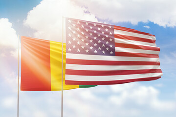 Sunny blue sky and flags of united states of america and guinea