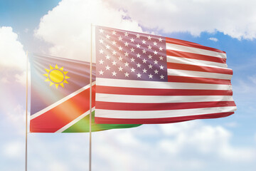 Sunny blue sky and flags of united states of america and namibia