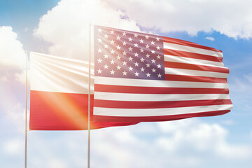 Sunny blue sky and flags of united states of america and poland