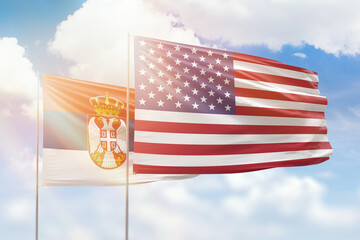Sunny blue sky and flags of united states of america and serbia
