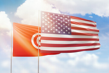 Sunny blue sky and flags of united states of america and tunisia
