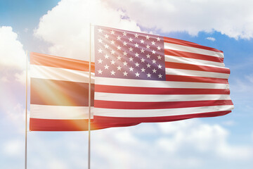 Sunny blue sky and flags of united states of america and thailand