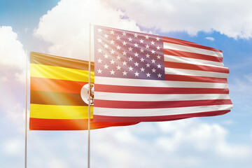 Sunny blue sky and flags of united states of america and uganda