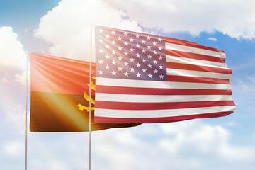 Sunny blue sky and flags of united states of america and angola