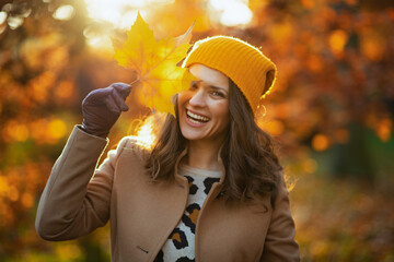 happy modern woman in beige coat and orange hat