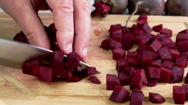 Slicing purple raw beet into small cubes.