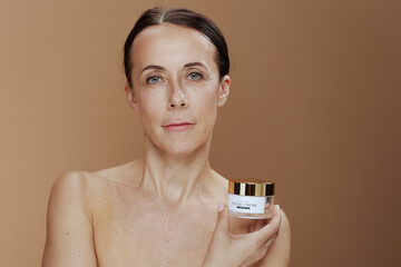 modern woman with facial cream jar isolated on beige background