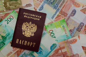 The Russian passport lies on paper banknotes in denominations of 50, 100, 200, 500, 1000 and 5000 rubles. Money on credit from a bank secured by documents. Financial crisis in Russia. Top view