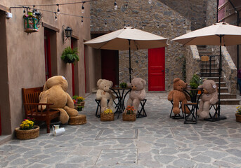 Big Teddy bears at the table in a street restaraurant in a new medieval italian tuscany style town...