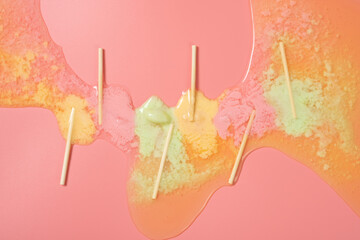 melted colorful little popsicles on a pink background
