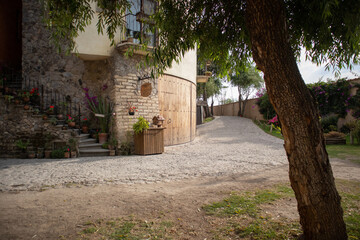 alley street with a graden and a tree at one side and an old house in a medieval italian tuscany...