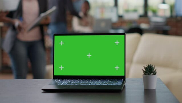 Laptop with green screen display on desk in business office, team of people having isolated blank copy space with chroma key backgorund and mockup template. Modern technology. Close up.