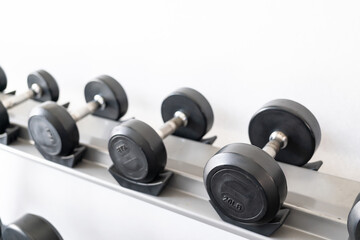 Obraz na płótnie Canvas Stand with dumbbells. Sports and fitness room. Weight Training Equipment. Black dumbbell set, many dumbbells on rack in sport fitness center