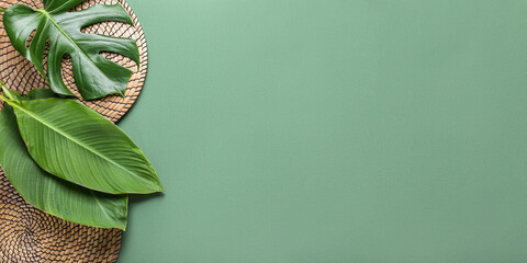 Tropical leaves and wicker mats on green background with space for text