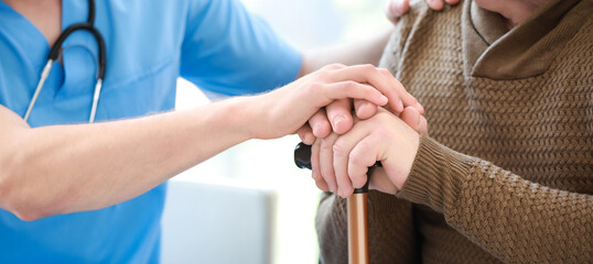Medical worker with senior man in nursing home, closeup