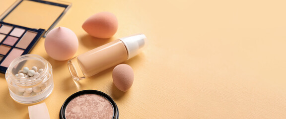 Makeup sponges and different cosmetics on beige background with space for text