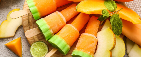 Board with tasty melon popsicles on light background