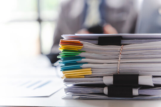 Stack of documents, pile of papers on office desk employee's table, closeup, Asian people.