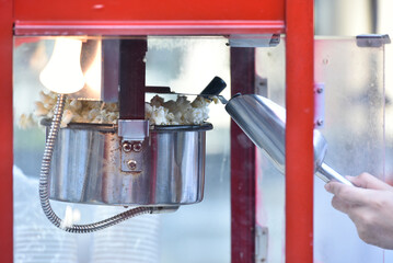 Hand holding metal spoon checking Popcorn in popcorn machine