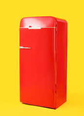 Stylish retro fridge on yellow background