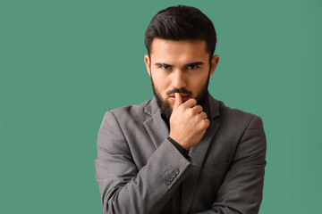 Portrait of pensive bearded man on green background