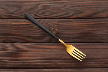 Stylish stainless steel fork on dark wooden background