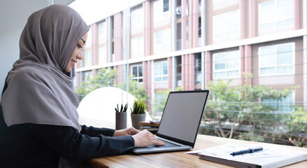 Happy arab woman freelancer chatting with clients on laptop, sitting at cafe, empty space