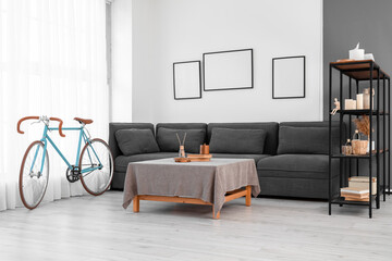 Interior of modern living room with bicycle, black sofa and shelving unit