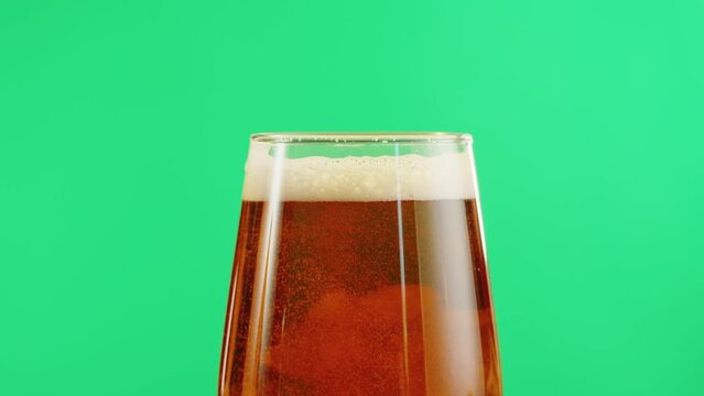 Foamy beer in glass close-up. Alcohol golden beer drink in mug. Fresh pale ale on green chroma key background. 