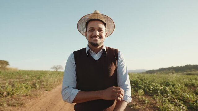 Portrait of young man with crossing hands in the casual shirt in the farm on the colorful sky background. Cinematic 4K