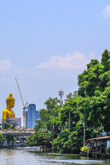 Bangkok,Thailand on May1,2020:Big golden Buddha statue named "Phra Buddha Dhammakaya Thepmongkhon"(under construction) and white pagoda of Wat Paknam Phasi Charoen.