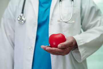 Asian woman doctor holding red heart for health in hospital.