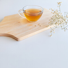 cup of tea on wooden board with flowers and white background