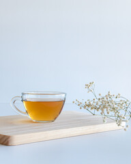 cup of tea on wooden board with flowers and white background