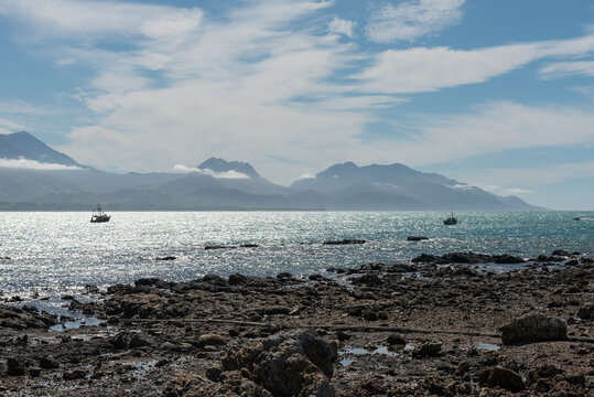 The View Across The Bay At Kaikoura From The Peninsula To The Kaikoura Ranges. Two Commercial Fishing Boats At Anchor Offshore. Kaikoura, Canterbury, South Island, New Zealand.