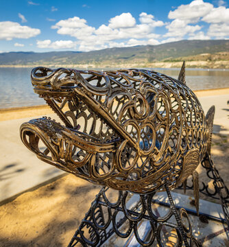 Metal sculpture of fish on a beach of Penticton BC Canada. Art object in the shape of an salmon fish